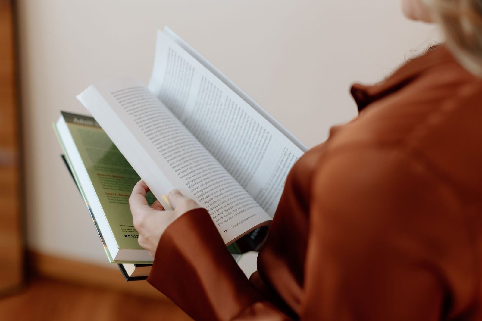 woman reading books about learning styles while wearing a burnt orange shirt